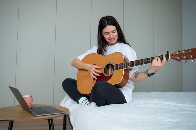 Woman playing guitar at home during quarantine