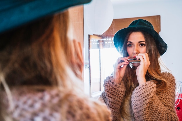 Woman playing harmonica near mirror