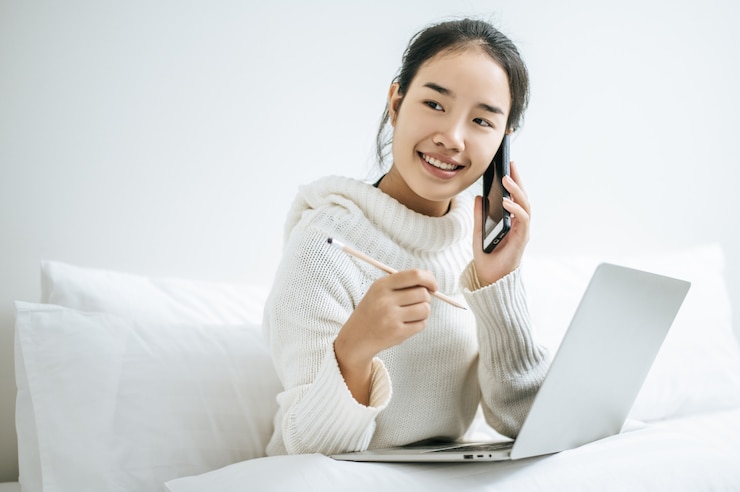無料Photo ノートパソコンを演奏し、電話で話している女性。