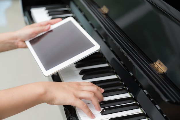 Woman playing piano hand holding a tablet