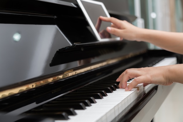 Woman playing piano and using her digital tablet