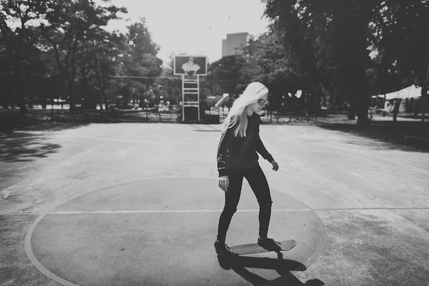 Женщина играет на скейтборде в баскетбольной площадке