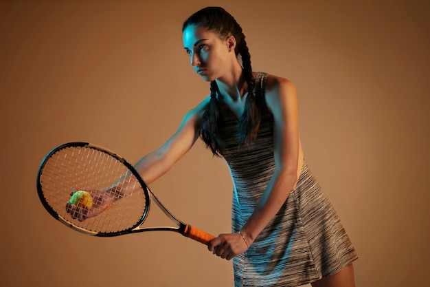 Donna che gioca a tennis isolato sulla parete marrone