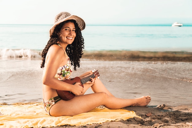 Бесплатное фото Женщина играет на гавайской гитаре у моря