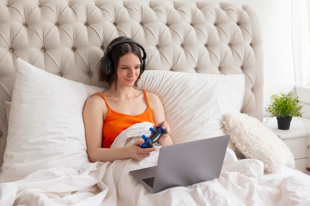 Woman playing videogames in bed