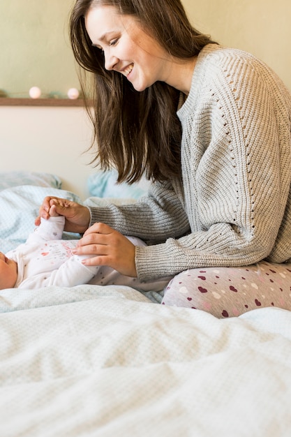 Woman playing with baby on bed 