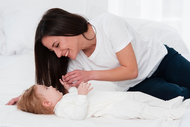 Woman playing with baby in bed