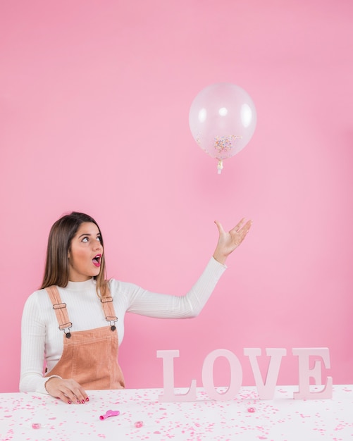 Woman playing with balloon near Love inscription 