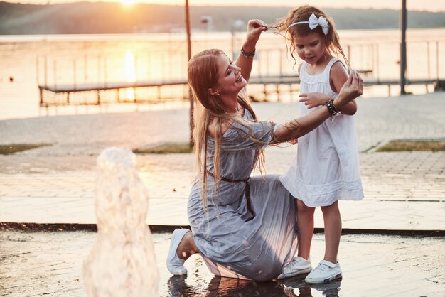 A woman playing with a child near the ocean in the park at sunset