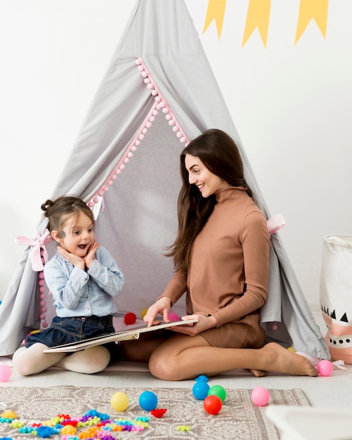 Donna che gioca con la ragazza felice in tenda