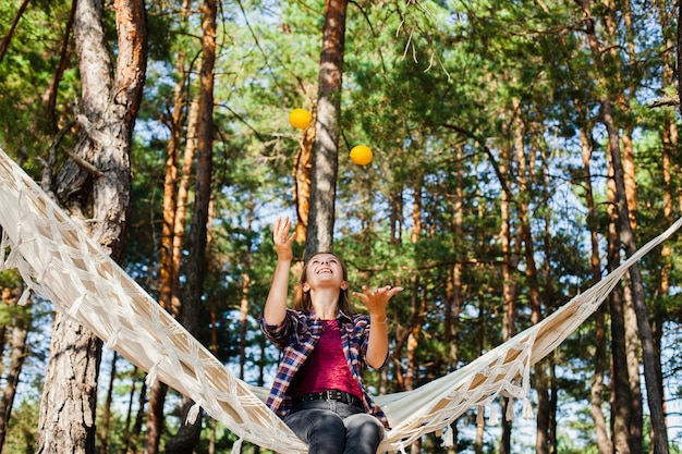 Woman playing with lemons in hammock