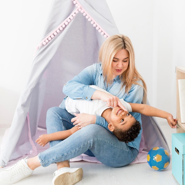 Woman playing with young boy next to tent