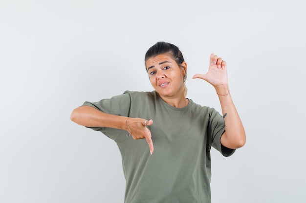 woman pointing down and to the side in t-shirt and looking confident.