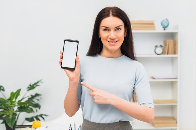 Woman pointing finger at smartphone with blank screen