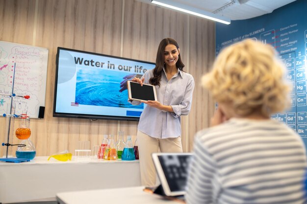 Woman pointing finger at tablet screen showing students