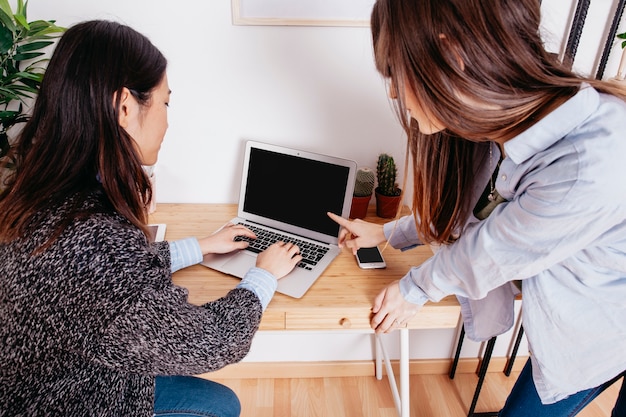 Woman pointing at laptop of colleague