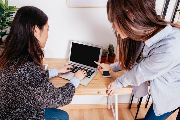 Woman pointing at laptop of colleague