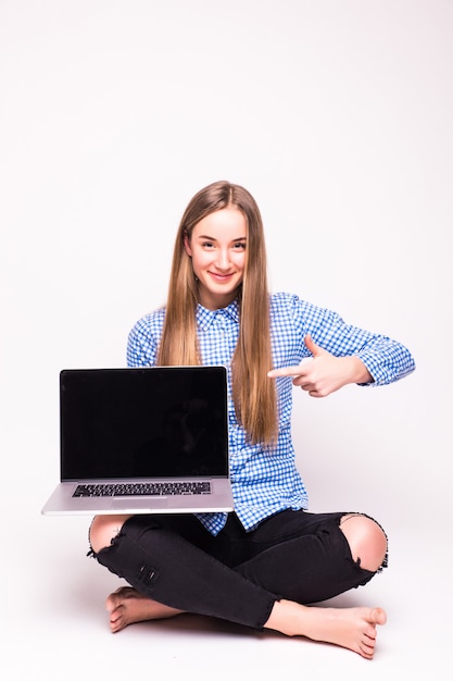 Donna che punta a un computer portatile - isolato su un muro bianco