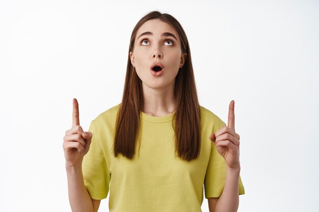 woman pointing, looking up with excited face impressed by something above on white