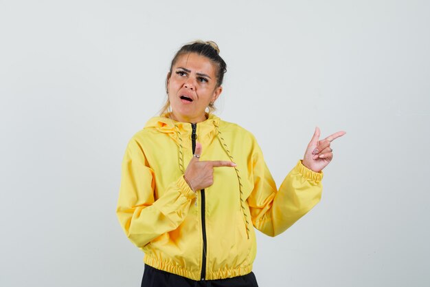 Woman pointing to the side in sport suit and looking hesitant. front view.