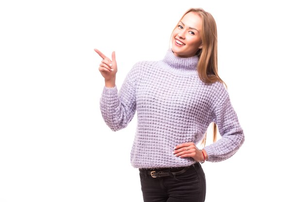 Woman pointing to the side standing in full length - isolated on white wall.