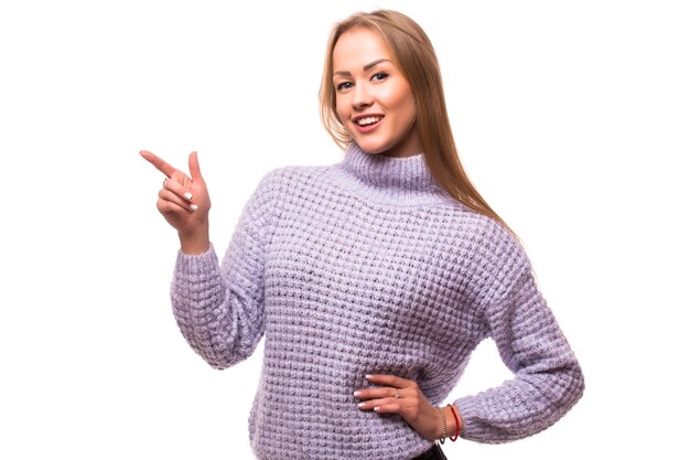 Woman pointing to the side standing in full length - isolated on white wall.