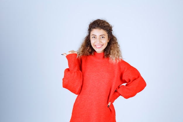 Foto gratuita donna che indica qualcosa dietro e sorridente.