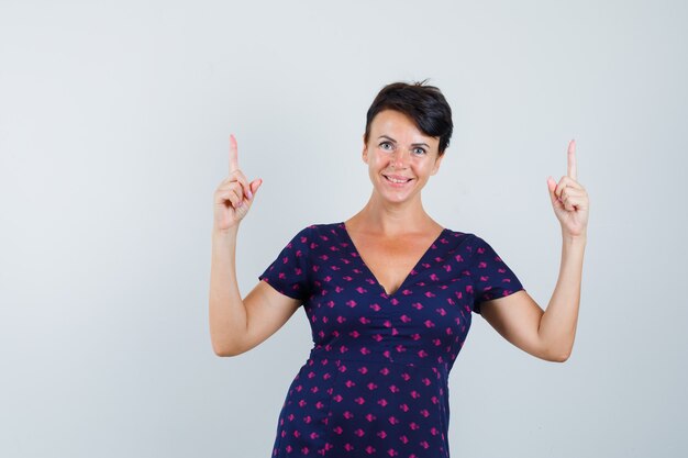 Woman pointing up in dress and looking confident