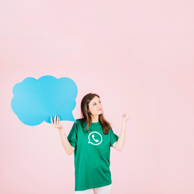 Woman pointing upwards holding empty blue speech bubble