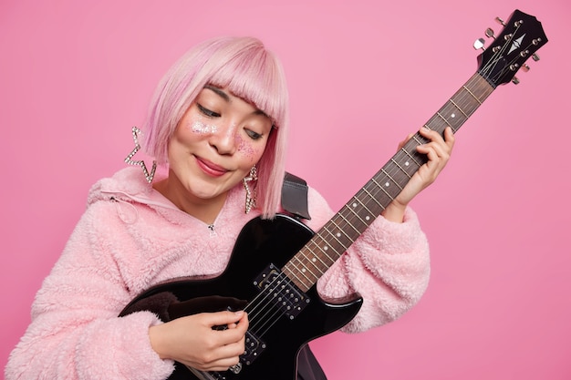 Woman pop band singer plays acoustic electric guitar wears fashionable clothes