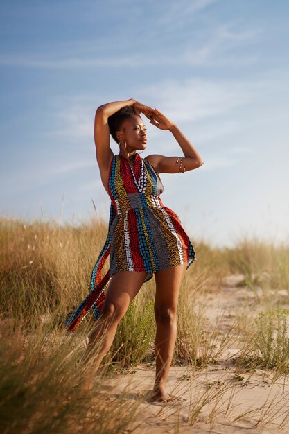 Foto gratuita donna in posa in un ambiente arido mentre indossa abiti nativi africani