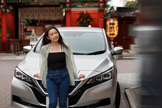 Foto gratuita donna in posa accanto alla sua nuova auto elettrica