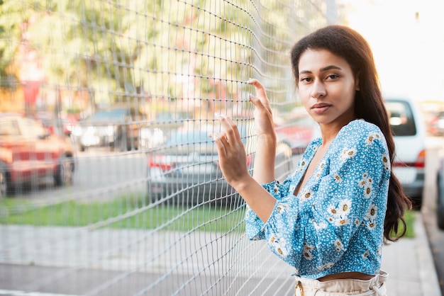 女性がポーズし、有線フェンスに彼女の手を保つ