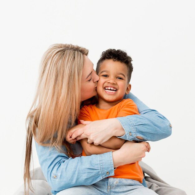 Woman posing  and kissing smiley young boy
