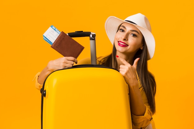 Woman posing next to luggage and pointing at travel essentials