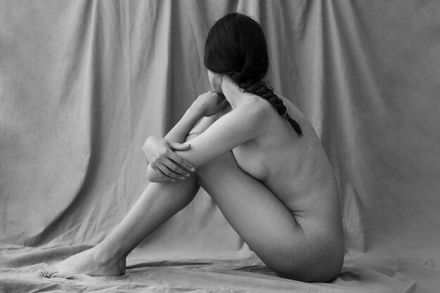 Woman posing nude in studio full shot