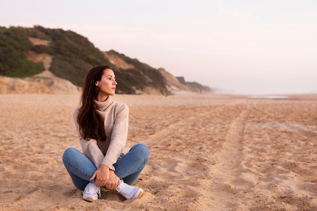 Foto gratuita donna in posa sulla sabbia in spiaggia con copia spazio