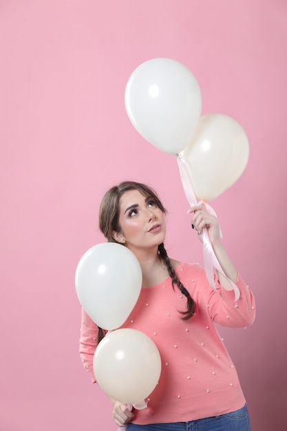 Woman posing while holding sets of balloons