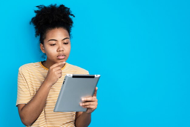 Woman posing while thinking and holding tablet