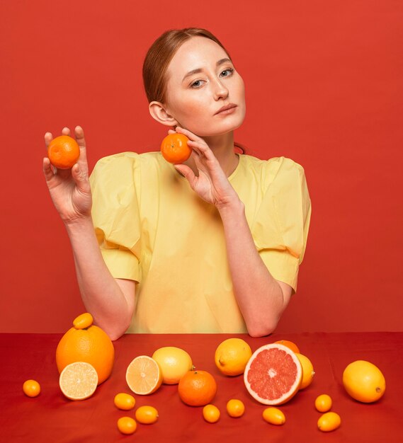 citruses의 배열과 함께 포즈를 취하는 여자