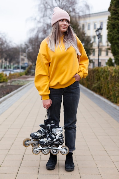 Woman posing with beanie and holding roller blades