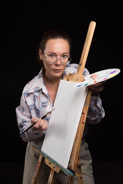 Free photo woman posing with brushes and canvas on black . high quality photo