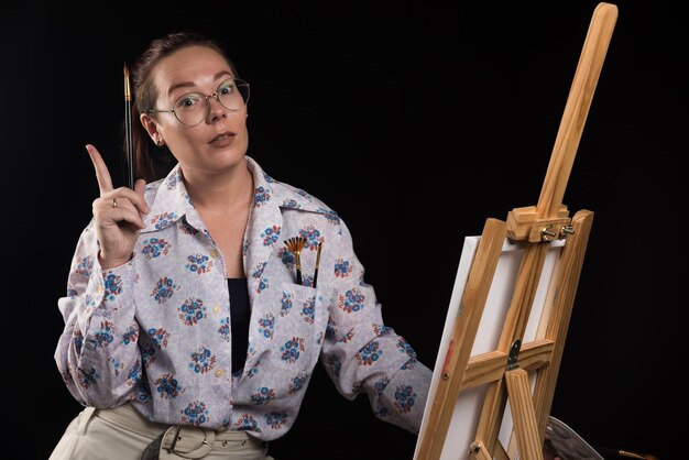 Free photo woman posing with brushes and canvas on black . high quality photo