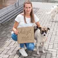 Foto gratuita la donna che posa con il cane e che tiene mi adotta il segno per animale domestico