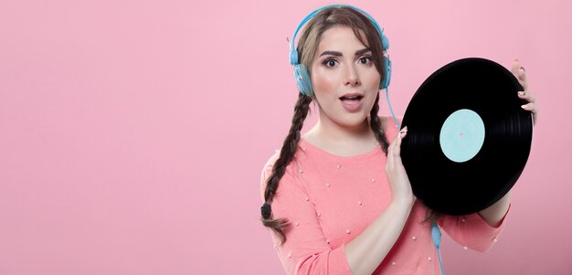 Woman posing with headphones and holding up vinyl record