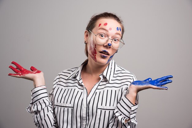 Woman posing with paints on her face on gray background . High quality photo