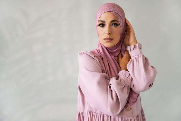 핑크 히잡 미디엄 샷으로 포즈를 취하는 여성