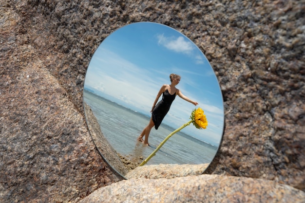 Woman posing with round mirror and flower