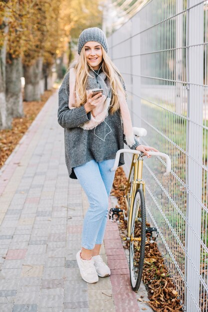 Woman posing with smartphone and bicycle