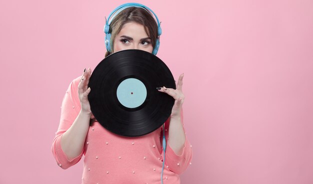 woman posing with vinyl record while wearing headphones